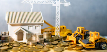 House,,Crane,And,Construction,Truck,Models,With,Gold,Coins,Spilling